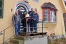 Drei Herren und zwei Frauen stehen vor der Eingangstür des sanierten ehemaligen Forsthauses in Lehenbach.