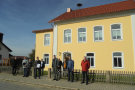 Eine Gruppe Männer stehen in der Sonne vor einem gelben Haus.