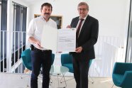 Zwei Herren stehen im Innenbereich der Konzeller Mitte und halten eine Auszahlungsurkunde in ihren Händen
