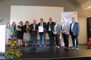 Fünf Damen und fünf Herren während eines Gruppenfotos im Rahmen der Preisverleihung auf der Bühne im Bürgerhaus Zeilarn