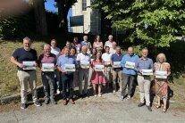 20 verantwortliche Personen stehen vor dem Treppenaufgang zu einer Kirche und halten eine Infobroschüre in ihren Händen.