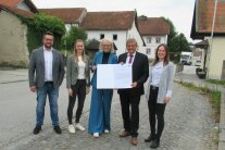 Drei Damen und zwei Herren stehen in der Ortsmitte von Jahrdorf und halten eine Urkunde in ihren Händen.