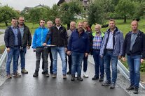 Elf Herren stehen nebeneinander auf der erneuerten Obstgartenstraße in Zueding.