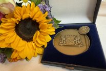 Die Staatsmedaille in Bronze – links daneben ein Sonnenblumen-Gesteck