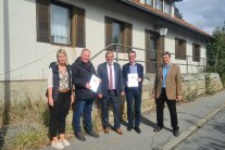 Eine Dame und vier Herren stehen vor dem abrissreifen Haus „Dora“ in Klingenbrunn