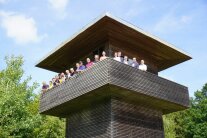 18 Menschen posieren bei strahlendem Sonnenschein auf dem Limes-Wachturm bei Hienheim für ein Gruppenfoto.