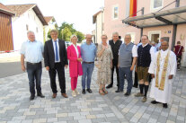 Zwei Frauen und sieben Männer stehen auf dem neugestalteten Dorfplatz