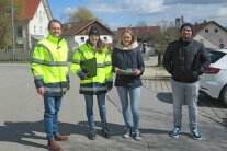 Zwei Herren und zwei Frauen stehen auf einer asphaltierten Straße im Ortskern von Malgersdorf. Im Hintergrund sind mehrere Häuser der Ortschaft und ein blauer Himmel mit einigen Wolken zu sehen.