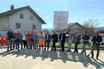 15 Personen posieren nebeneinander für den symbolischen Spatenstich im Ortskern Richardsreut.