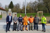 Eine Dame und sechs Herren stehen vor dem Kriegerdenkmal in Wolfakirchen.