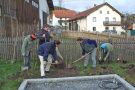 Fünf Bürger beteiligen sich mit Schaufeln und Schubkarren an einer neuen Anpflanzung entlang eines eingezäunten Bauerngartens in der Ortschaft Biberbach, Lkr. Freyung-Grafenau.