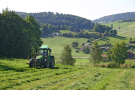 Ein Traktor mäht die Wiese zur Heuernte im hügeligen bayerischen Wald bei Lichtenau im Lkr. Freyung-Grafenau.